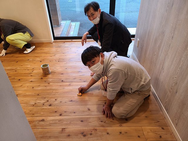 神戸の注文住宅の杉フロアーにミツロウワックスを塗るスタッフ