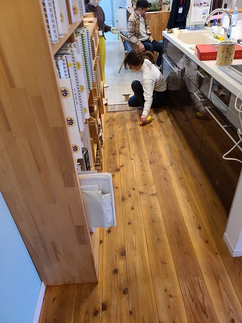 神戸の注文住宅の杉フロアーにミツロウを塗るスタッフ