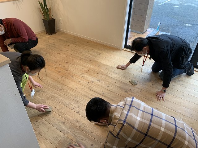 神戸の注文住宅の杉フロアーを磨くスタッフたち